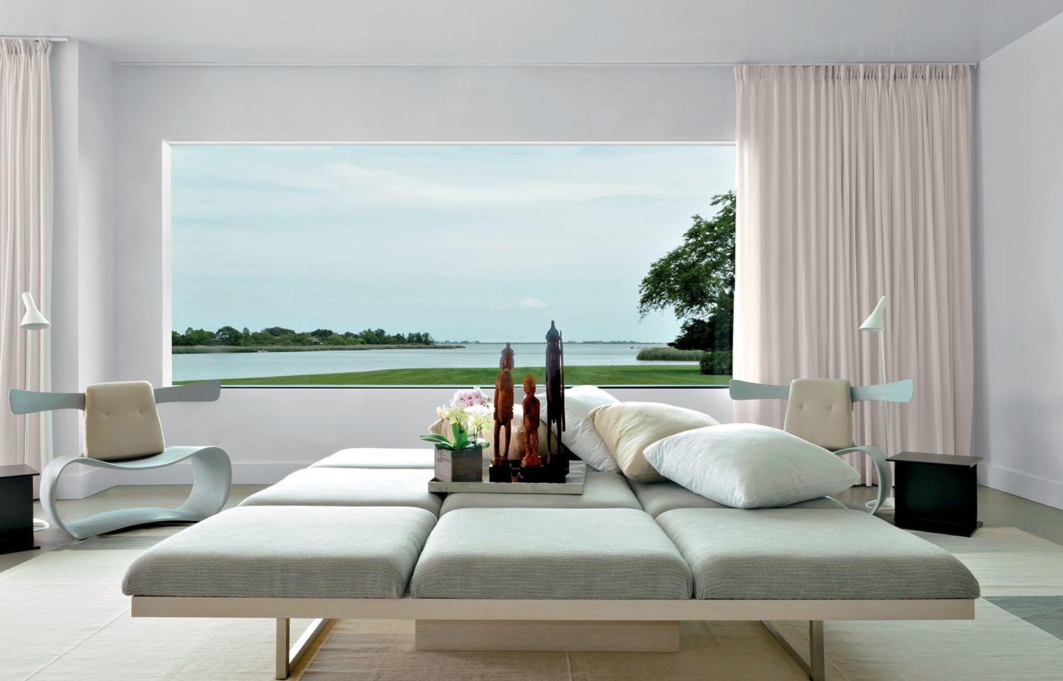 A cozy living room featuring a couch, a table, and a large window letting in natural light.